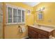 Well-lit bathroom with a single vanity, shuttered window, and bright yellow paint at 3109 Ion Ave, Sullivans Island, SC 29482
