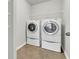 Functional laundry room with tile flooring, ample shelving, and modern, full-size washer and dryer units at 423 Watershed Dr, Goose Creek, SC 29445