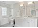 Bright bathroom with a double vanity, white cabinets, decorative patterned floor tiles, and a tiled tub at 43 Hasell St, Charleston, SC 29401