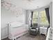 Charming bedroom with a crib, glider chair, floral wall art, and ample natural light at 4621 Holmes Ave, North Charleston, SC 29405