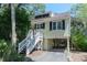 Charming beach house on stilts with black shutters, well-maintained landscaping, and a welcoming staircase to the front door at 554 Double Eagle Trce, Seabrook Island, SC 29455