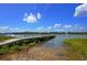 Scenic view of a wooden dock extending into calm waters, framed by lush greenery under a clear blue sky at 555 Double Eagle, Seabrook Island, SC 29455