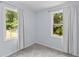 Sunlit bedroom with gray carpet, two windows providing ample natural light, and neutral paint, creating a calm atmosphere at 7239 Commodore Rd, Hollywood, SC 29449