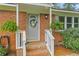 Close-up of a charming brick home's entry, showcasing the decorated door and lush greenery at 7239 Commodore Rd, Hollywood, SC 29449