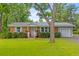 Charming brick home featuring a manicured lawn, mature landscaping, and an attached side garage at 7239 Commodore Rd, Hollywood, SC 29449