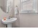 Stylish half bathroom featuring a pedestal sink, round mirror, and natural light from the window at 104 Hyacinth St, Summerville, SC 29483