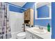 Traditional bathroom with blue walls, white tile, and a vanity with a wooden storage cabinet above the toilet at 1060 Oakcrest Dr, Charleston, SC 29412