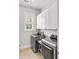 Well-lit laundry room with stainless steel washer and dryer, storage cabinets and a window with shutters at 1527 Wando View St, Charleston, SC 29492