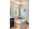 Modern soaking tub with a tile surround next to a large shuttered window for lots of natural light at 1527 Wando View St, Charleston, SC 29492