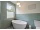 Serene bathroom with a freestanding tub, green tile, and a sunlit window at 1603 Culpepper Cir, Charleston, SC 29407