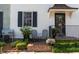 Inviting brick porch with wrought iron railing, chairs, and lush plantings near the front door at 166 1/2 Queen St, Charleston, SC 29401