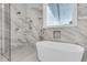 Bright bathroom showcasing a luxurious soaking tub and elegant marble finishes at 1761 Old Military Rd, Charleston, SC 29412