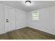 Bedroom with light hardwood floors, a white door, and a window with white trim at 1915 Quitman St, North Charleston, SC 29405