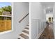 A well-lit staircase with wainscoting and a light wood railing leads to a hall with wood flooring at 1989 Groveland Ave, North Charleston, SC 29405