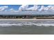 Wide beach view featuring ocean waves, a sandy shoreline, and a condominium complex at 216 W Arctic Ave # 9, Folly Beach, SC 29439