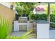 Outdoor kitchen with stainless steel grill, granite countertop and mini fridge nestled in a lush backyard setting at 2449 Daniel Island Dr, Daniel Island, SC 29492