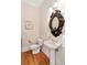 Chic half bath with decorative mirror, elegant pedestal sink, and hardwood floors at 26 Beachwood East, Isle of Palms, SC 29451