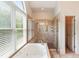 Bright bathroom featuring a soaking tub with a shower and a large window, providing natural light at 26 Beachwood East, Isle of Palms, SC 29451