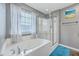 Modern bathroom with soaking tub, shower, tile floors, and natural light from the window at 3055 Nantuckett Ave, North Charleston, SC 29420