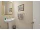 A half-bathroom with a stylish pedestal sink, mirror and decorative art provides convenience for guests at 315 Clubview Rd, Summerville, SC 29485