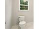 Clean bathroom featuring white toilet and marble floors, illuminated by natural light at 317 Sabal Palmetto Ct, Moncks Corner, SC 29461
