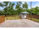 Backyard view of a wooden deck and storage shed, surrounded by a verdant lawn and trees at 323 Amy Dr, Goose Creek, SC 29445