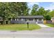 Gray brick ranch-style home with a green lawn, surrounded by mature trees at 323 Amy Dr, Goose Creek, SC 29445