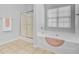 Bright bathroom featuring a large soaking tub with a window, a separate shower with glass doors, and neutral tile flooring at 334 Cicadas Song Dr, Moncks Corner, SC 29461