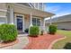 Inviting front porch with stylish columns, manicured shrubs and walkway with red mulch at 334 Cicadas Song Dr, Moncks Corner, SC 29461