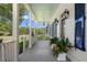 Inviting front porch with blue-painted ceiling, lanterns, and potted flowers and lush landscaping at 3426 Acorn Drop Ln, Johns Island, SC 29455