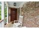 Inviting front porch with brick facade, rocking chair and dark wood front door at 36 Nicholson St, Charleston, SC 29407
