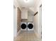 Compact laundry area with stackable washer and dryer, exposed brick wall, and decorative tile flooring at 36 Nicholson St, Charleston, SC 29407