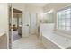 Bright bathroom with a bathtub, large window, and a door leading to another room at 465 Blue Dragonfly Dr, Charleston, SC 29414