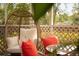 Comfortable lounge area with a swing chair and chairs with red pillows on a bright and sunny screened porch at 465 Blue Dragonfly Dr, Charleston, SC 29414