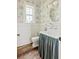 Cozy bathroom with patterned wallpaper, unique sink with fabric skirt, and hardwood floors at 4855 Retriever Rd, Wadmalaw Island, SC 29487