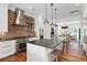 Spacious kitchen with large island, brick accent wall, stainless steel appliances, and hardwood flooring at 4855 Retriever Rd, Wadmalaw Island, SC 29487