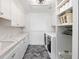Well-appointed laundry room with modern washer and dryer, white cabinetry, and shelving maximizes functionality at 4855 Retriever Rd, Wadmalaw Island, SC 29487
