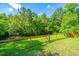 Grassy backyard featuring a sturdy fence, mature trees, and partial view of a pond at 493 Nelliefield Trl, Wando, SC 29492