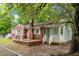 Charming brick home with light blue door and shutters surrounded by mature trees and a fenced yard at 5056 Piedmont Ave, North Charleston, SC 29406