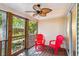 Enjoy the outdoors from this screened porch with dual red chairs and a ceiling fan at 525 Tayrn Dr, Wando, SC 29492