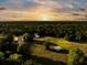 Stunning sunset aerial of property featuring a horse barn, lush greenery, and serene pond at 5348 Mccullough Dam Rd, Wadmalaw Island, SC 29487