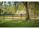 Pastoral view of barn behind wooden fence shaded by mature trees draped in Spanish moss at 5348 Mccullough Dam Rd, Wadmalaw Island, SC 29487