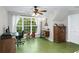 Bright bedroom with large window, light walls, green wood floors, ceiling fan, and home office setup at 5348 Mccullough Dam Rd, Wadmalaw Island, SC 29487