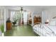 Bright bedroom featuring a large window with a view of the forest, green painted wood floors, and vintage furniture at 5348 Mccullough Dam Rd, Wadmalaw Island, SC 29487
