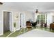 Well-lit bedroom with green painted wood floors, white trim, ceiling fan, large window with nature view, and vintage style bed at 5348 Mccullough Dam Rd, Wadmalaw Island, SC 29487