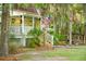 Inviting home exterior featuring a covered front porch, an American flag, and lush greenery at 5348 Mccullough Dam Rd, Wadmalaw Island, SC 29487