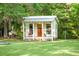 Quaint guest house with covered porch, rocking chair, boat to the side, and surrounded by a lush, green lawn at 5348 Mccullough Dam Rd, Wadmalaw Island, SC 29487