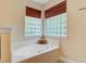 Bright bathroom featuring a soaking tub with jets nestled under two glass block windows for natural light and privacy at 9524 Markley Blvd, Summerville, SC 29485