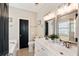 Bright bathroom featuring a double vanity, two mirrors, and a black door at 116 W 2Nd St, Folly Beach, SC 29439