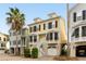 Charming yellow townhome with black shutters, white trim, stairs leading to double front doors, and a ground-level garage at 116 W 2Nd St, Folly Beach, SC 29439